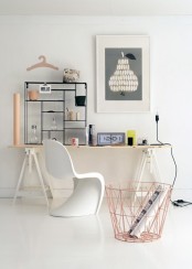 a Scandinavian home office with a white and stained trestle desk, a white sculptural chair, a black shelving unit and artwork