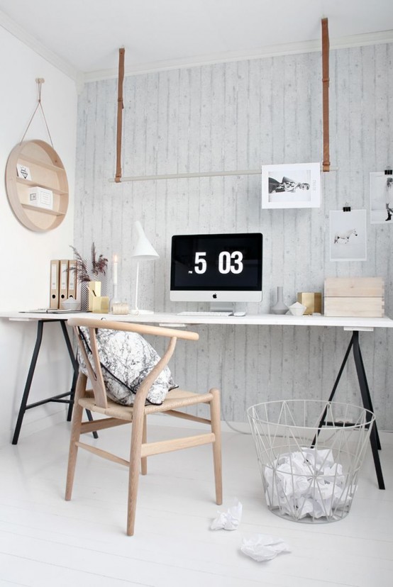 a Scandinavian home office with a black and white trestle desk, a neutral chair, a hanging holder and a round wall-mounted wooden shelf