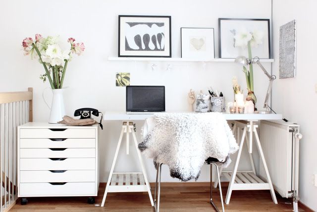 A white Scandinavian home office nook with a trestl desk, a chair, a gallery wall and a small file cabinet is a lovely space