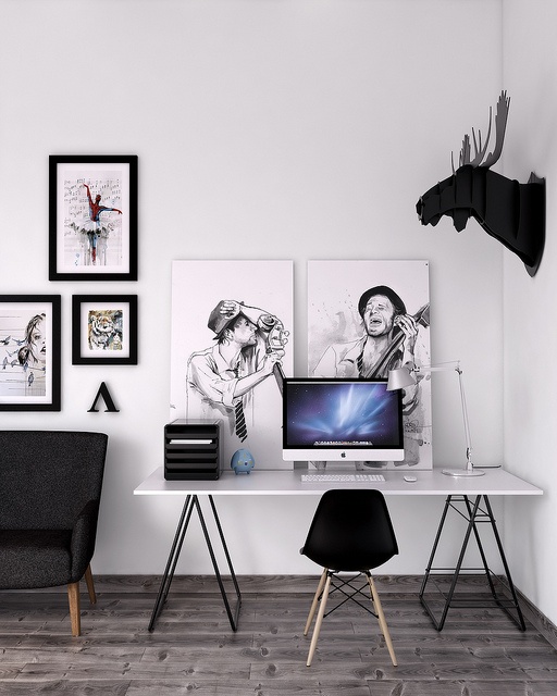 a laconic black and white Scandinavian home office nook with a trestle desk, a black chair, black and white artworks, faux taxidermy and other stuff