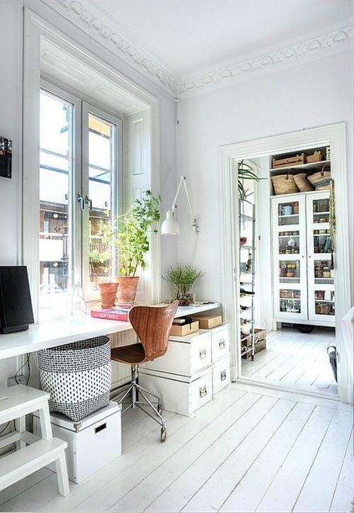 a vintage Scandinavian home office done in white, with a shared desk, boxes for storage, potted plants and lots of natural light