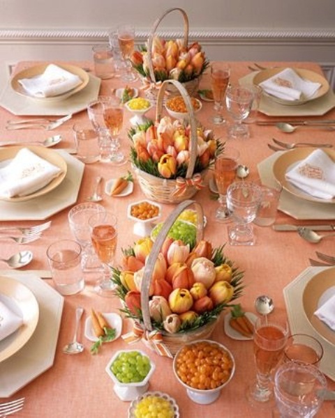 a colorful spring tablescape with a peachy pink tablecloth, bright tulip centrpieces in baskets, and gilded touches