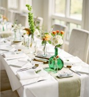 a fresh spring table setting with colorful bloom centerpieces, white napkins, a green runner and white porcelain