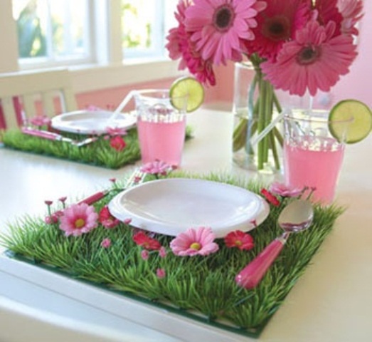 a colorful place setting with a faux grass and bloom placemat and a hot pink bloom centerpiece