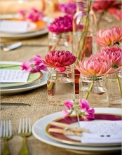 a colorful rustic spring setting with a burlap tablecloth, bright floral centerpieces and plates