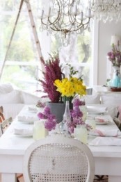 a neutral spring table setting with bright floral centerpieces in purple and yellow