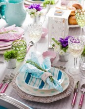 a colorful place setting with striped and polka dot plates and colorful glasses