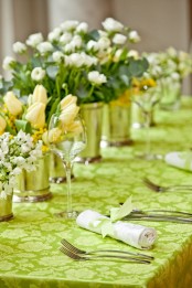 a green printed tablecloth, lush white and yellow flower centerpieces for spring