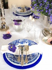 a spring place setting with printed blue plates and purple blooms
