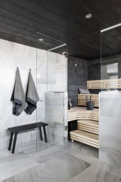 a steam room clad with black tiles and with wooden benches on several levels plus built-in lights
