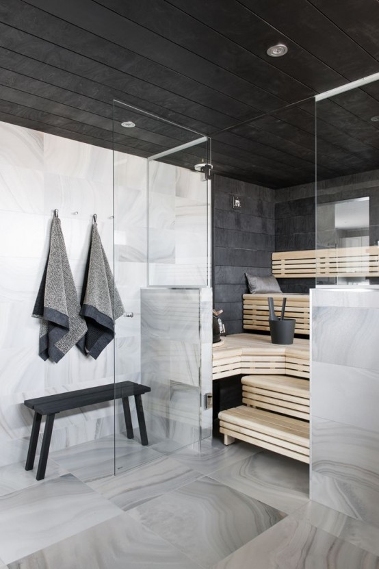 a steam room clad with black tiles and with wooden benches on several levels plus built-in lights