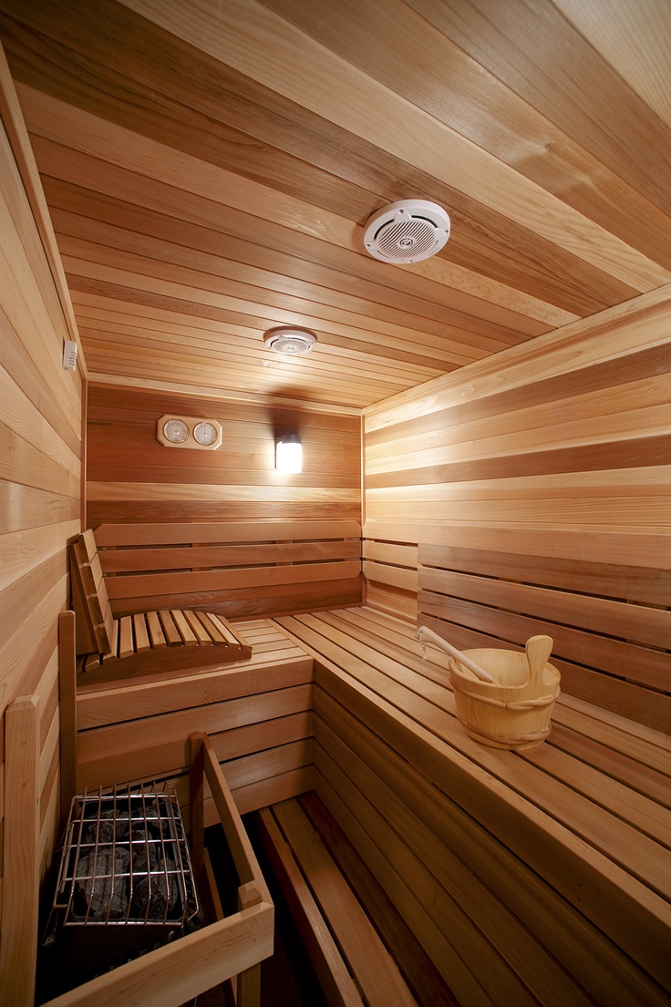 A super cozy steam room clad with wood, with benches at various levels and some built in lights