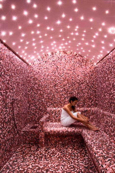 a pink steam room clad with mosaic tiles and with built-in lights that show off a sky is very romantic