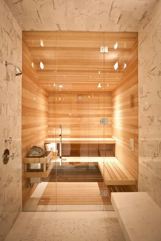 a cozy steam room fully clad with wood, with some benches and built-in lights plus glass doors is amazing