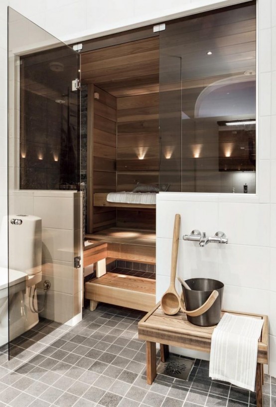 a small steam room clad with wood, with benches at several benches and built-in lights and smoke glass doors
