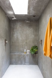 a fully concrete bathroom with a skylight, modern fixtures and tropical leaves feels and looks minimalist