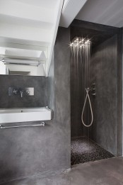 a minimalist concrete bathroom with a small shower space, a built-in vanity with a sink and a mirror over the sink