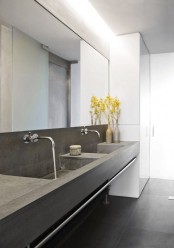 a minimalist bathroom with a double concrete vanity with built-in sinks, a large mirror and a mirror wardrobe right here