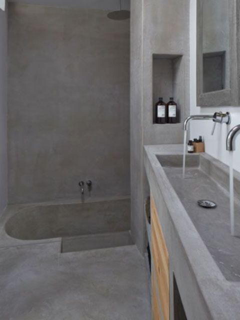 A minimalist concrete bathroom with a built in tub and a vanity with a double sink in one is rather wabi sabi