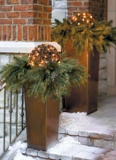 Tall metallic planters with evergreens and vine balls with lights will make your porch and outdoor space holiday like and festive