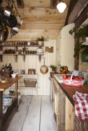 a cottage kitchen with neutral planked walls, rough wood cabinets and butcherblock countertops, a stained table kitchen island and open shelves