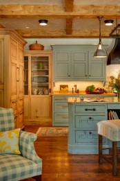 an inviting cottage kitchen with stained and blue cabinets, wooden beams on the ceiling, vintage metal pendant lamps and a printed upholstery