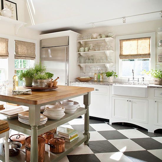 a cottage kitchen with vintage white cabinets, a subway tile backsplash, a grey table kitchen island and woven shades plus a checked floor