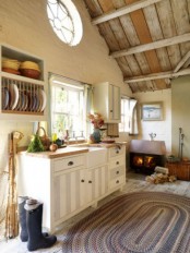 a neutral cottage kitchen with white and striped cabinetry, butcherblock countertops, a reclaimed wooden ceiling, an open storage unit and a pretty oval rug