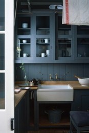 a modern cottage kitchen with graphite grey cabinets and a backsplash, butcherblock countertops and a built-in sink plus white porcelain