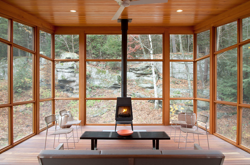 Super cozy sunroom filled with natural wood and a wood burning stove