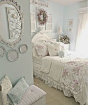 a pastel blue shabby chic bedroom with refined white furniture, floral bedding, decorative plates and shutters and potted blooms