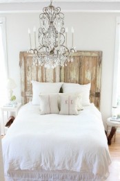 a neutral shabby chic bedroom with a shabby wooden screen, a crystal chandelier, refined vintage furniture