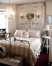 a vintage to shabby chic bedroom in neutrals, with a wooden statement wall, a forged bed, vintage furniture, a crystal chandelier