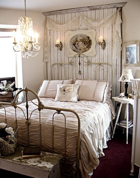 a vintage to shabby chic bedroom in neutrals, with a wooden statement wall, a forged bed, vintage furniture, a crystal chandelier