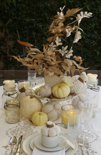 a delicate white rustic Thanksgiving tablescape with white linens, porcelain, pumpkins, a white knit coverup for the vase is elegant