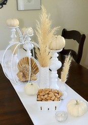 white linens, white pumpkins, pampas grass and candlesholders shaped as pumpkins for a chic rustic Thanksgiving tablescape
