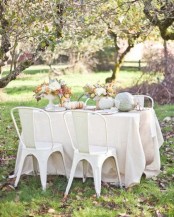 white linens, white chairs, pastel and whitewashed pumpkins, white blooms and greenery for a chic Thanksgiving look