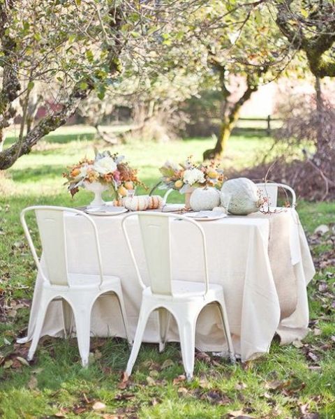 white linens, white chairs, pastel and whitewashed pumpkins, white blooms and greenery for a chic Thanksgiving look