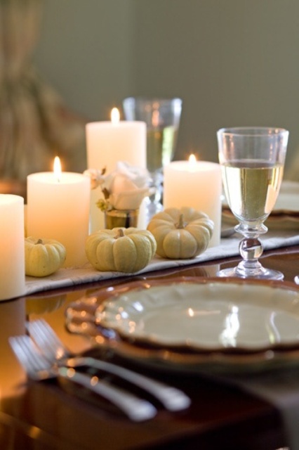 white linens, mini pumpkins, candles and white roses plus white porcelain with a gold edge give a refined yet rustic look to the table