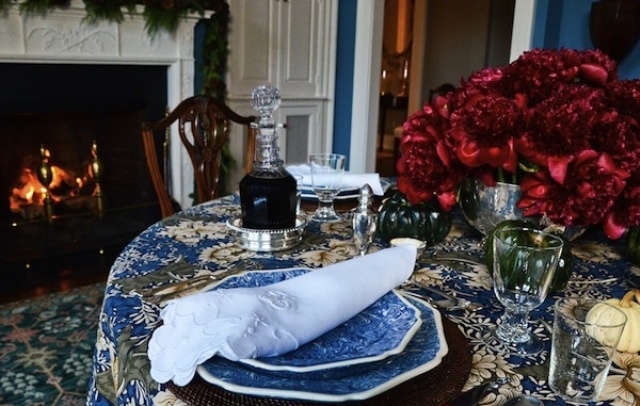 A patterned blue tablecloth and blue porcelain plus red blooms and gold touches for a chic and elegant tablescape