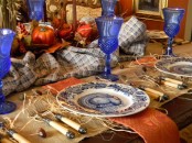 a traditional Thanksgiving tablescape in orange and blue, with burlap, hay, pumpkins and blue glasses