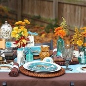 brown and turquoise table setting with bright blooms, woven placemats, owls and brown napkins