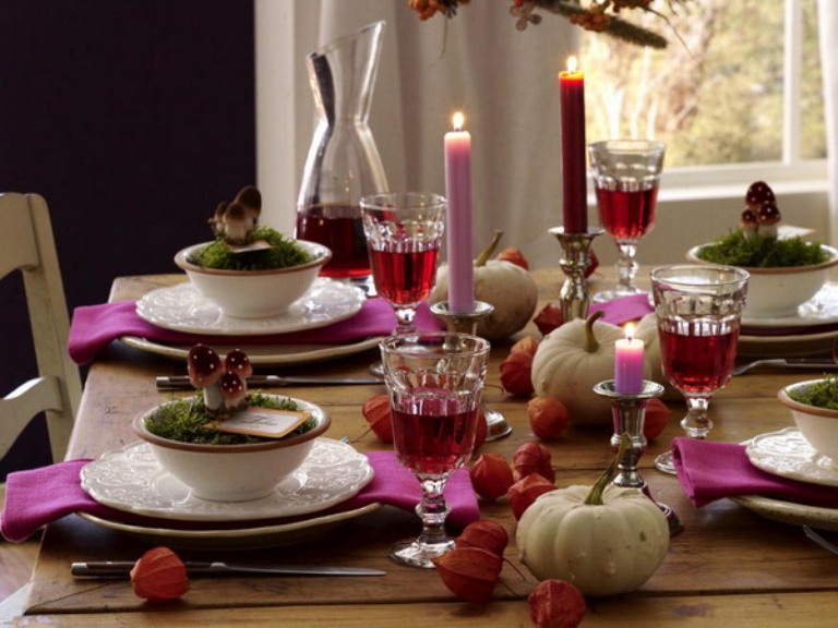 A colorful woodland themed Thanksgiving tablescape with hot pink napkins, a hot pink and burgundy candle, mushrooms, moss and some dried seed pods and gourds is awesome