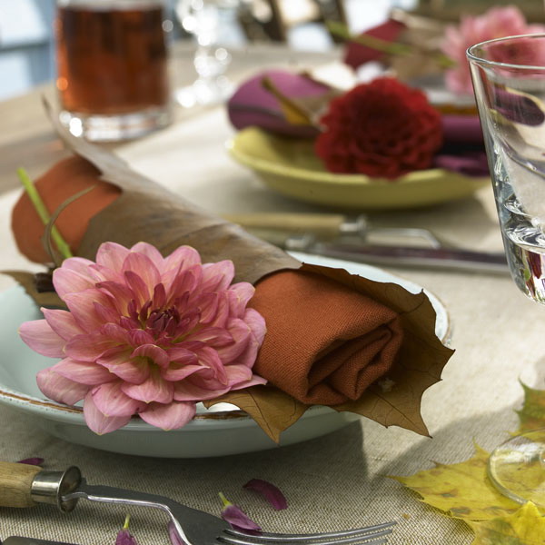 Rust napkins covered with fall leaves and with pink blooms will make your tablescape cool and chic, very fall like