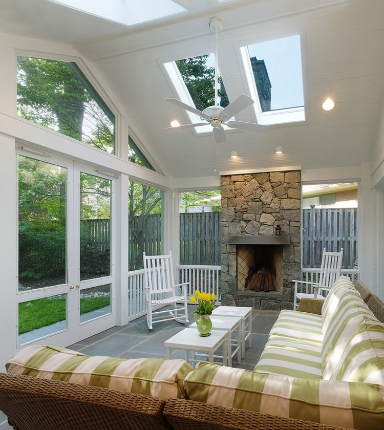 this screen porch addition features a ceiling fan and a fireplace so owners are able to cool down or warm up the place