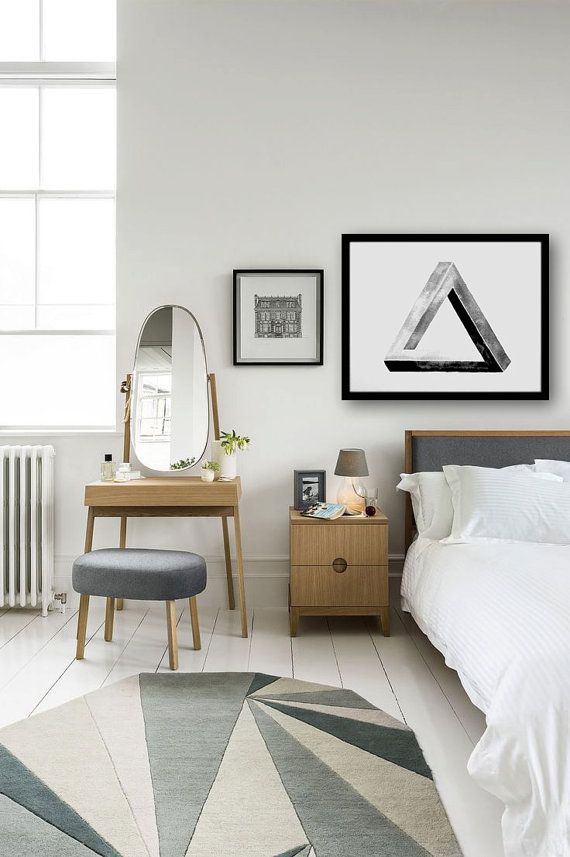 A neutral modern bedroom with light stained furniture, white bedding, a pretty geometric rug that makes a statement, graphic artwork and a mirror