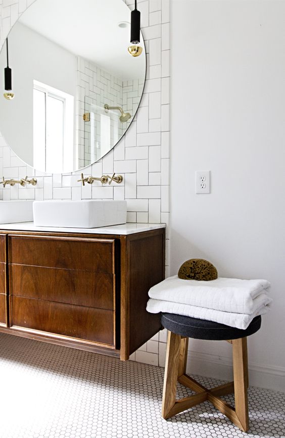 A chic mid century modern bathroom in neutrals, with subway and hex tiles, a dark stained vanity and stool and pendant lamps