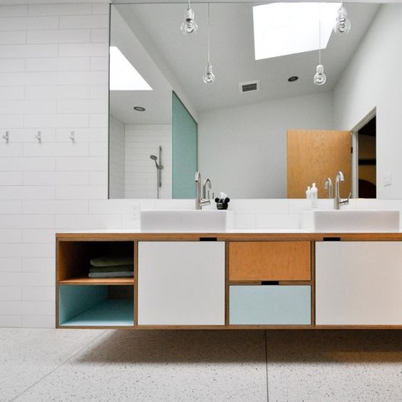 A creative mid century modern bathroom in neutrals, with a color block vanity and pendant lamps