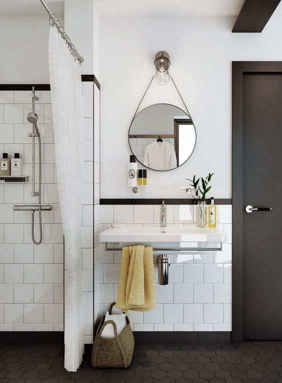 A stylish white and graphite grey mid century modern bathroom with grey hex tiles on the floor and a round mirror and a floating sink