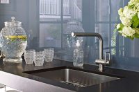a stainless steel kitchen with black countertops and a blue glass backsplash for a super modern and bold look
